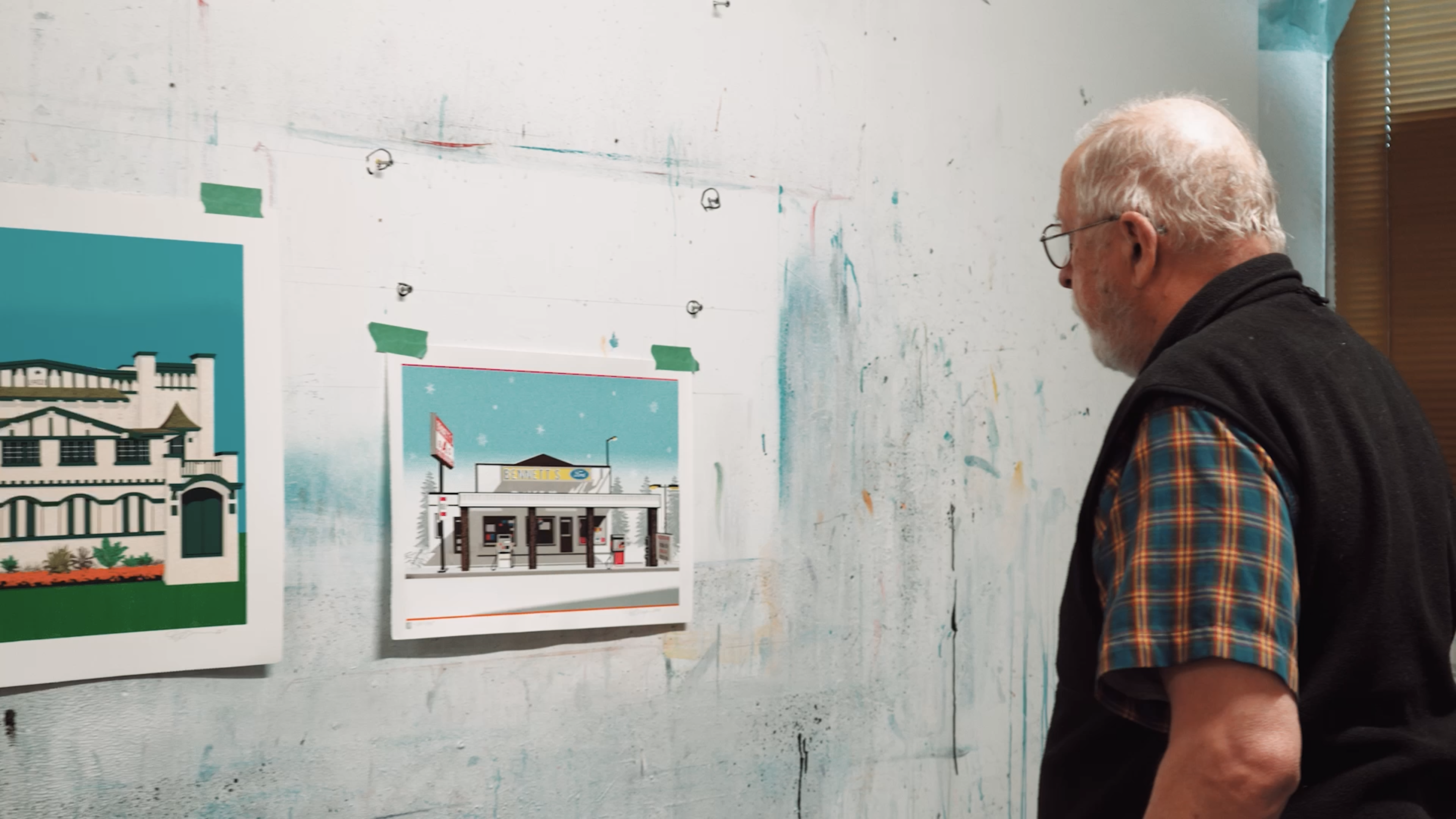 Artist David Thauberger looks at two of his prints on a wall in his studio.